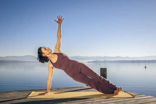 Woman practice yoga asana on paddle board at night